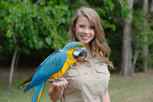 Bindi Irwin with Queto the Blue-and-gold Macaw on her arm.